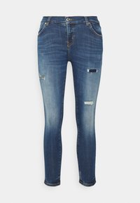 Jeans de denim azul ajustados con ligeros desgastes y parches deshilachados en las rodillas, con un clásico diseño de cinco bolsillos y pasadores para cinturón.