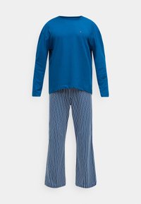 Blaues Langarm-T-Shirt mit Rundhalsausschnitt und kleinem Logo, kombiniert mit marineblau-weiß gestreiften Schlaghosen. Baumwollmaterial, legeres Design.