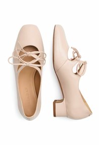 Scarpe in pelle rosa chiaro con punta quadrata, dotate di fianchi sagomati e un tacco basso. Lacci annodati aggiungono un tocco di eleganza al design superiore.