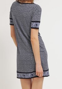 Marindress med blommönster, kort ärm och svarta detaljer vid ärmarna och fållen. Mjuk tyg med en figurnära silhuett.