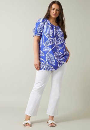 Blue short-sleeve top with white leaf pattern, elasticized neckline, paired with white straight-leg pants and white sandals.