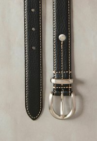 Cintura in pelle nera con finitura testurizzata, cuciture in contrasto color beige e fibbia in metallo argentato con design a doppia linguetta.