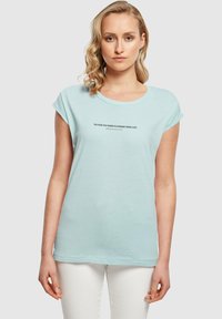 Lyseblåt kortærmet T-shirt lavet af blød bomuld, med en motiverende tekstprint centreret på brystet i sort.