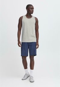 Szürke tank top, tengerészkék rövidnadrág, szürke edzőcipő, fehér zokni. Hétköznapi nyári öltözet klasszikus dizájnnal. Egyszerű anyagok, minták vagy díszítések nélkül.