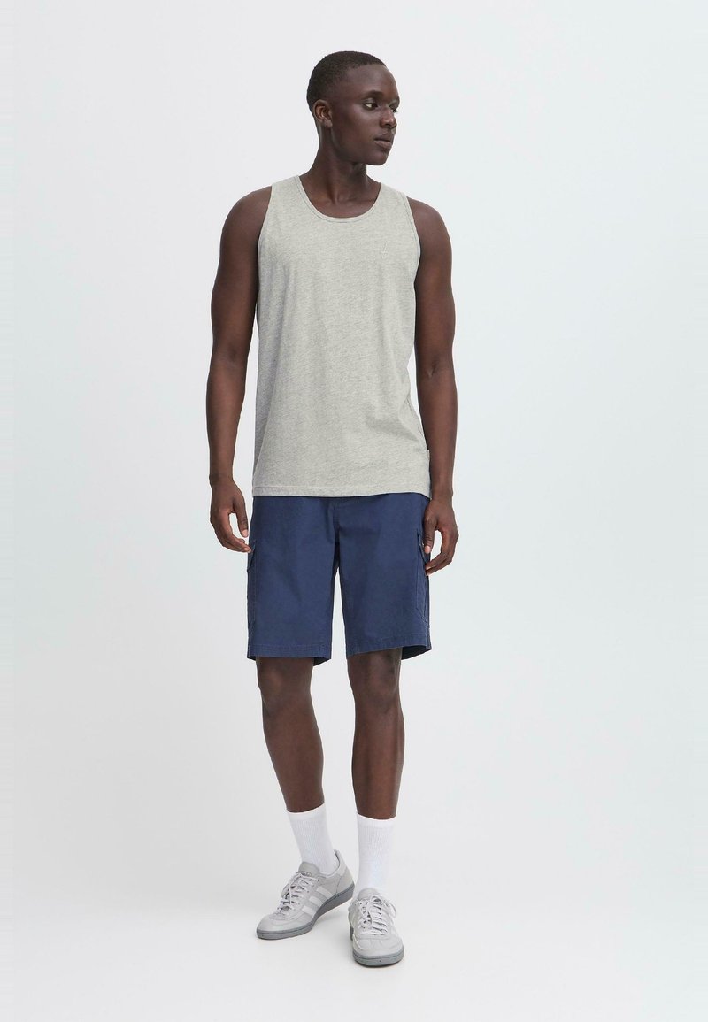Szürke tank top, tengerészkék rövidnadrág, szürke edzőcipő, fehér zokni. Hétköznapi nyári öltözet klasszikus dizájnnal. Egyszerű anyagok, minták vagy díszítések nélkül.