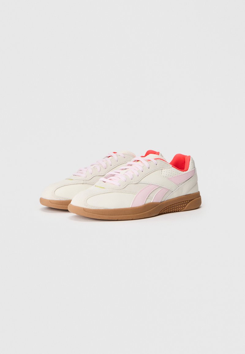 Sneakers bianchi con accenti rosa, caratterizzate da una suola texturizzata e dettagli perforati sui lati. Realizzate in tessuto leggero e materiali in gomma.