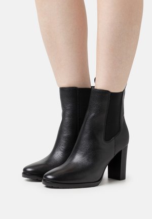 Bottines en cuir noir avec une finition texturée, un bout pointu et des panneaux latéraux élastiques. Le talon en bloc épais ajoute de la stabilité.