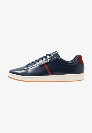Navy patent leather sneaker with white sole, red and navy striped accents, lace-up design, and branded silver detail on the side.