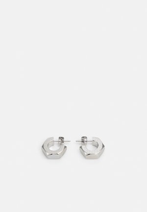 Paire de petites boucles d'oreilles créoles hexagonales en ton argent avec motif gravé et fermoirs à tige sur fond blanc.