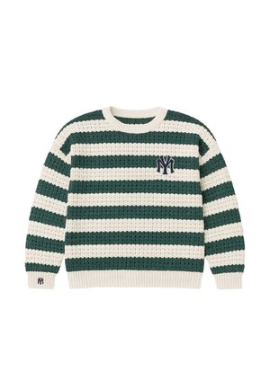 Mand iført en grøn- og hvidstribet strikket sweater med et emblem, bukser med nålestriber og en beige truckerhat med et logo.