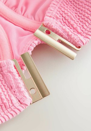 Rosa strukturiertes Gewebe mit gerafften elastischen Kanten und zwei flachen rechteckigen Metallhaken zum Befestigen.