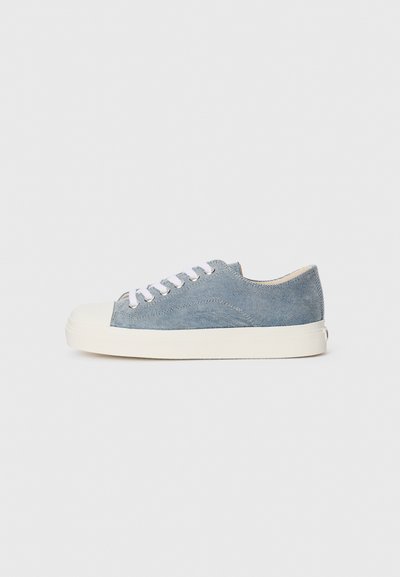 Denim sneaker in light blue, featuring a white rubber cap toe, white laces, and a minimalistic design with a textured upper.