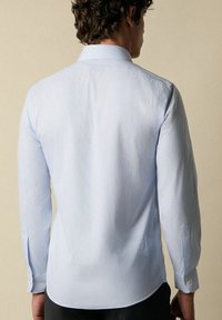 Hellesblaues gestreiftes Langarmhemd mit einem formellen Kragen, tailliertem Schnitt und geknöpften Manschetten. Glattes Material mit einem leichten Glanz.
