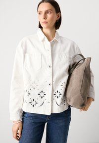 Valge denim jakk, mille allääres on lillelise lõikega disain, kahte rinna/taskut ja hõbedased nööbid; koos halli sametist käekotiga.