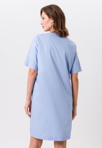 Himmelblaues Kurzarmkleid mit lockerer Passform, aus glatter Stoffqualität. Es hat einen einfachen, runden Ausschnitt und endet oberhalb des Knies.