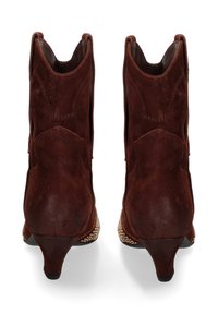Stivaletti in suede marrone con punta affusolata, tacco basso e decorazioni in oro a forma di borchie lungo i lati. Dettagli di cucitura minimi.