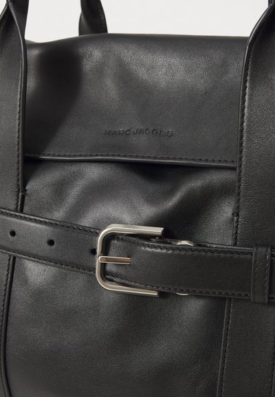 Zaino in pelle nera con texture liscia, spallacci larghi con fibbia argentata e marchio in rilievo sul pannello frontale.