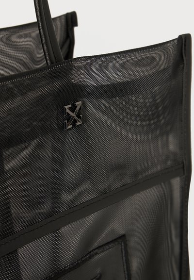 Τσάντα χειρός από μαύρο δίχτυ με μικρό μεταλλικό τετράγωνο λογότυπο που απεικονίζει διασταυρούμενα βέλη στο επάνω τμήμα.