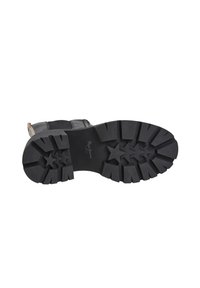 Suela de bota de goma negra con una profunda banda de rodadura, que presenta un patrón en forma de estrella y la marca "Pepe Jeans". Texturizada para tracción y durabilidad.