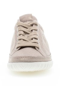 Beige suède sneaker met ronde neus, platte veters en witte rubberen zool. Heeft een zachte textuur en subtiele ontwerpelementen aan de zijkanten.