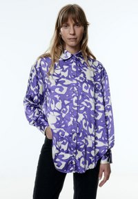 Paarse en witte gestreepte blouse met een relaxed fit, knoopsluiting, en lange mouwen, gemaakt van zachte stof.