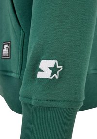 Zielona bawełniana bluza z kapturem z ribbowanymi mankietami i dołem, z białym haftowanym logo na rękawie. Gładka tekstura i standardowy krój.