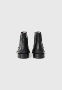 Sorte lær ankle støvler med en glat overflade, elastiske sidepaneler og en kontrasterende mat sål. Enkel, rund design med minimal pynt.