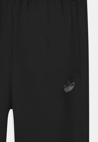 Svarta joggingbyxor gjorda av ett glatt tyg, med resårmidja och sidofickor, samt en liten vit logotyp på vänster lår.