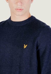 Maglione blu navy realizzato in tessuto testurizzato, con un colletto rotondo a coste e un piccolo logo giallo ricamato sul petto.