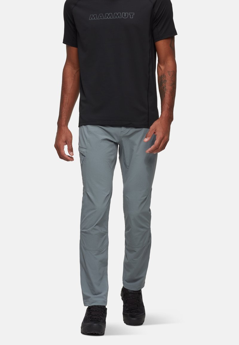 Szare spodnie outdoorowe wykonane z lekkiego materiału, o slim fit i kieszeniach cargo. W połączeniu z czarną koszulą z krótkim rękawem.