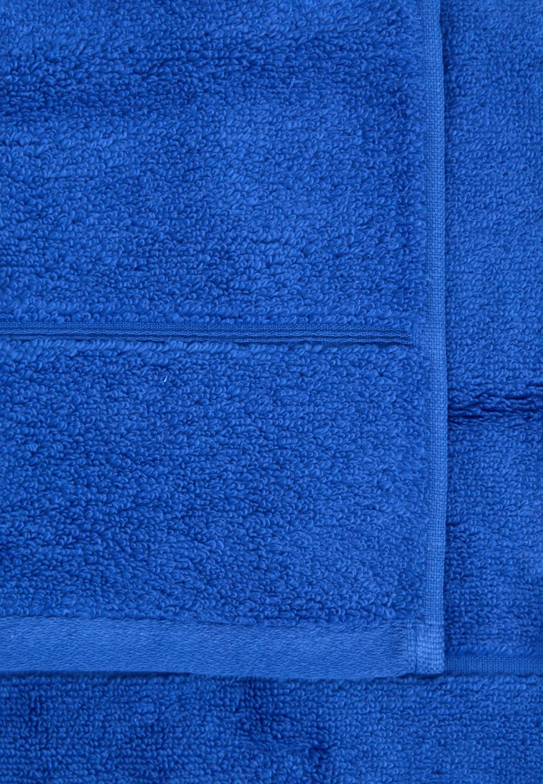 Niebieski ręcznik bawełniany o teksturowanej, pluszowej powierzchni z gładkim wykończeniem. Zakończony wzmocnioną krawędzią, prezentującą jednolity kolor i wzór.