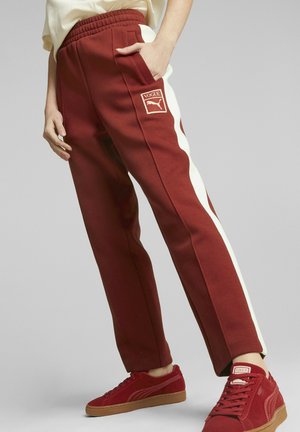 Mørkerøde joggerbukser med hvide side striber, elastisk talje og sidelommer. Bæres med matchende røde sneakers. Har logo-accenter.