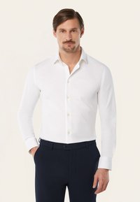 Witte lange mouwen shirt met een gespreide kraag, knoopsluiting en gouden knopen. Glad materiaal met een getailleerde pasvorm, gecombineerd met donkere broek.