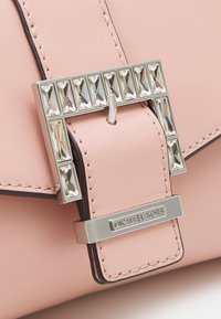 Borsa a mano in pelle rosa chiaro con fibbia argentata impreziosita da strass rettangolari e rifiniture nere. Incisione "MICHAEL KORS" sull'hardware.