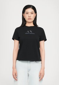 Juoda medvilninė marškinėliai su "AX" ir "Armani Exchange" logotipu mėlyna spalva. Trumpomis rankovėmis, apvaliu kaklu, laisvu kirpimu. Be raštų ar akcentų.