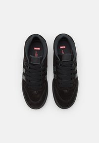 Black suede sneakers with grey accents, featuring a lace-up design, padded collar, reinforced toe, and two horizontal stripes.