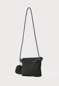 Musta kangasinen olkalaukku, jossa on kudottu sininen ja punainen hihna, vetoketjullinen suljin ja irrotettava mini-lompakko sivulla.