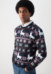 Sweater azul marinho com padrões de rena e flocos de neve em branco, vermelho e verde, apresentando punhos e bainha canelados, feito de tecido tricotado.