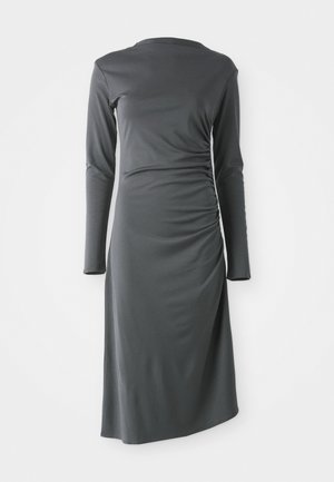 Vestido de manga larga en gris oscuro, fabricado con una tela suave. Presenta un detalle fruncido en el lateral y un dobladillo asimétrico.