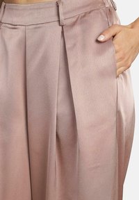 Helle rosa plissierte Hosen aus glattem Stoff, mit einer Seitentasche und maßgeschneiderem Bund für eine strukturierte Passform.