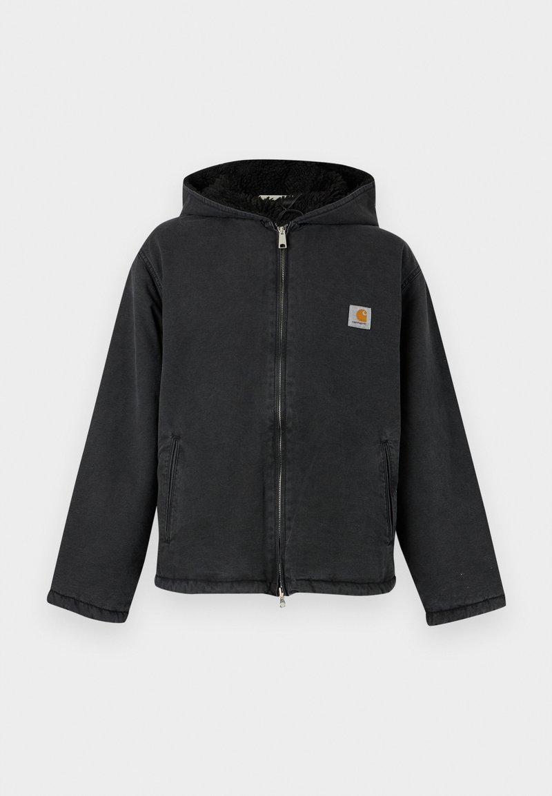 Veste noire zippée avec capuche, présentant une doublure en fourrure, des poches latérales et un patch logo carré sur la poitrine. Tissu robuste.