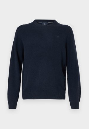 Jūrinės mėlynos spalvos apvalaus kaklo megztinis, pagamintas iš minkštos medžiagos, su ilgomis rankovėmis, karūnuotais manžetais ir apatine dalimi, su mažu logotipu ant krūtinės.