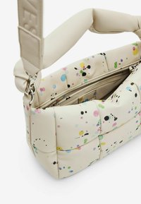 Beige gewatteerde handtas met kleurrijke spetterpatronen, voorzien van een ritssluiting en een brede, zachte schouderband voor comfort.