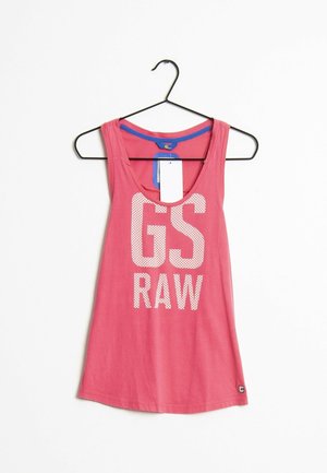 Pink ærmeløs top med hvid teksten "GS RAW" foran, hængende på en sort bøjle mod en hvid baggrund.