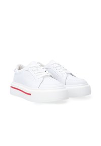 White sneaker made of smooth and perforated leather, featuring a thick rubber sole with a red accent band, laced front, and rounded toe.