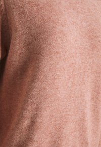 Maglione lavorato a maglia in una tonalità rosa morbida e tenue. La texture è liscia con un aspetto leggermente mélange, che evidenzia un tessuto fine e leggero.