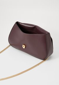Bordo torbica od umjetne kože sa strukturiranim dizajnom, koja ima zlatnu lančić strap i zlatnu kopču s dekorativnim kamenim akcentom.