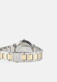 Silver and gold-tone stainless steel watch band with alternating rectangular links; round watch face with a reflective glass back.
