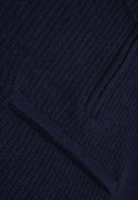 Mörk marinblå stickad tröja med en strukturerad, ribbad design och en liten, integrerad ficka fram. Mjukt garn med en mysig framtoning.
