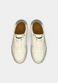 Ζευγάρι λευκά δερμάτινα αθλητικά παπούτσια με διάτρητες μύτες, λευκά κορδόνια και μπλε λεπτομέρειες στη φτέρνα, φαίνονται από πάνω σε λευκό φόντο.